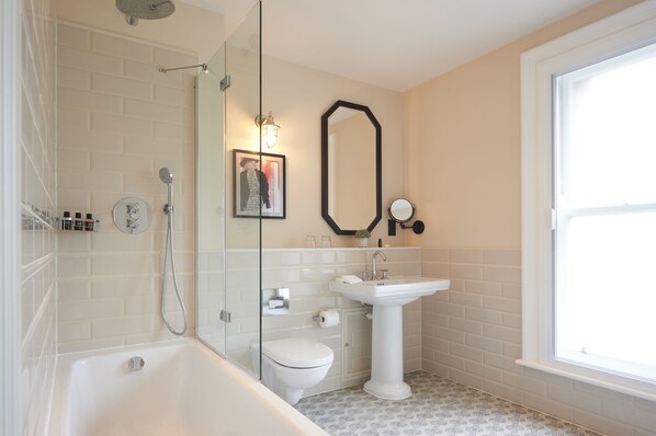 A modern bathroom with a glass-enclosed shower, a pedestal sink, and a toilet.