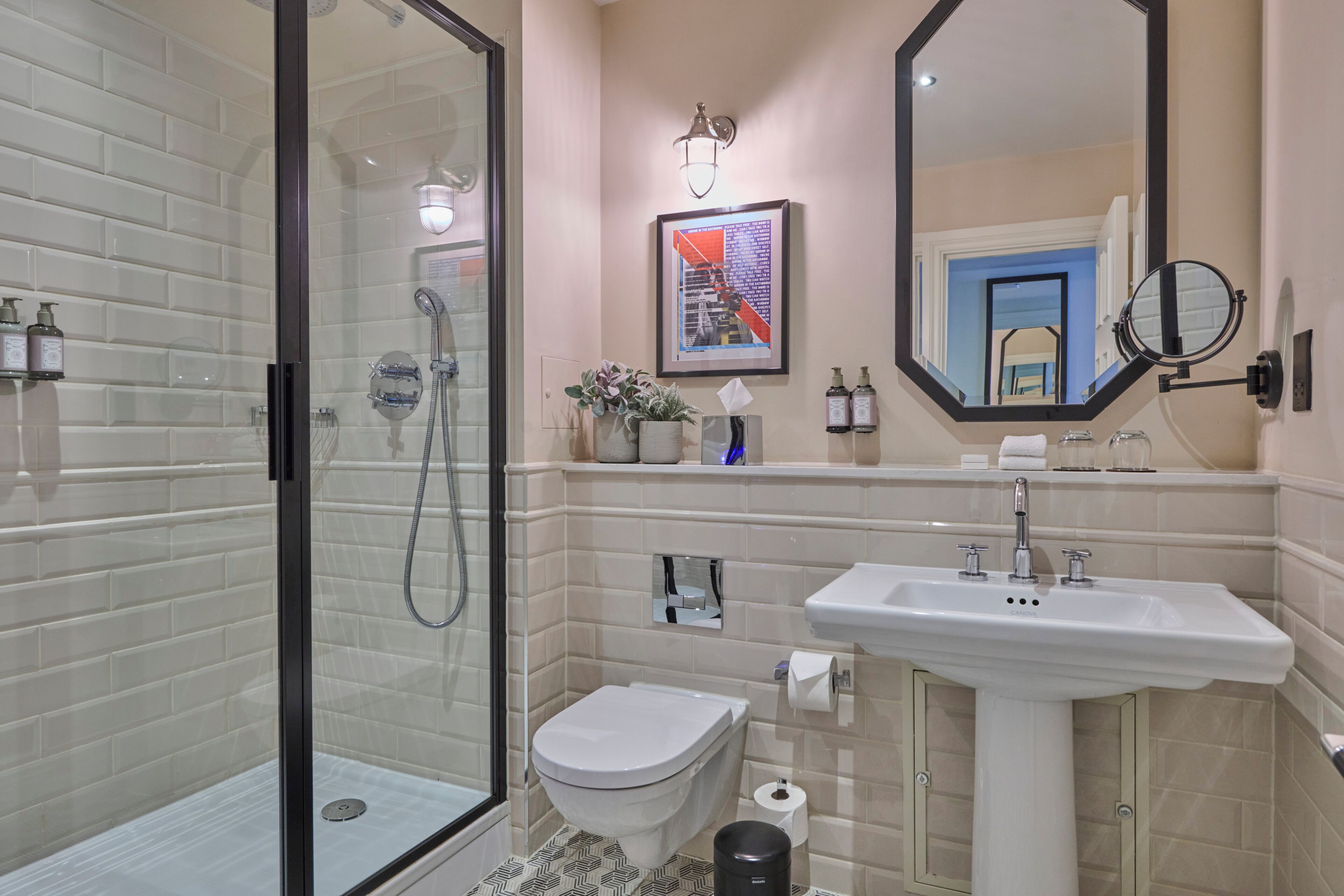 Un baño moderno con cabina de ducha de vidrio, inodoro blanco, lavabo y espejo.