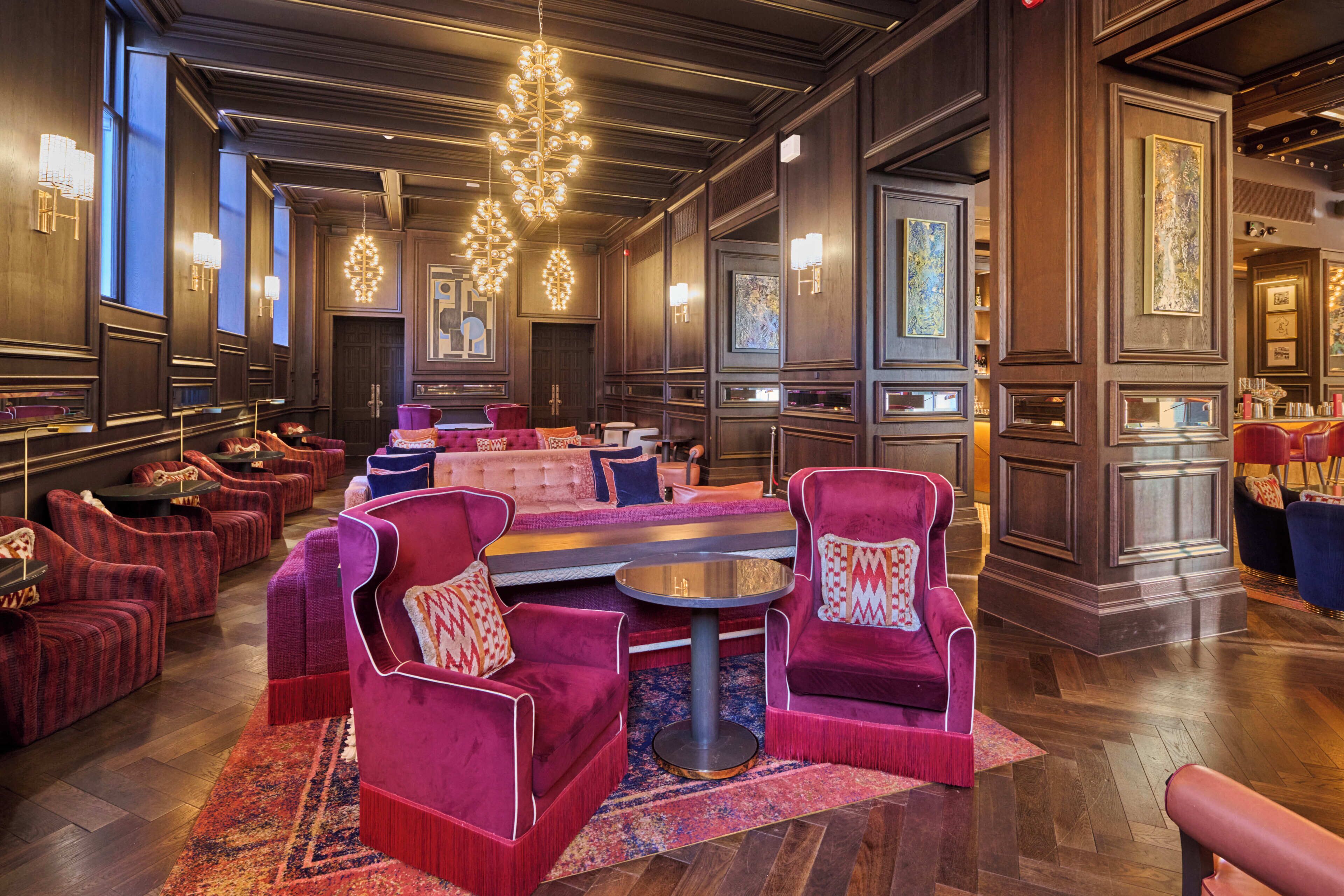 A luxurious hotel lobby with plush seating, a central coffee table, and elegant wall art.