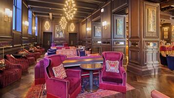 A luxurious hotel lobby with plush seating, a central coffee table, and elegant wall art.