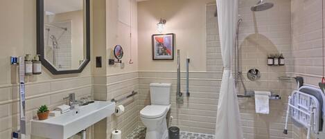 A bathroom with a sink, toilet, shower, and a large mirror.