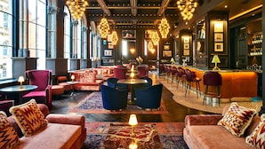 A spacious lounge area with multiple seating options, a bar, and large windows providing natural light.