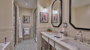 A modern bathroom with a large mirror, two sinks, a shower, and patterned floor tiles.