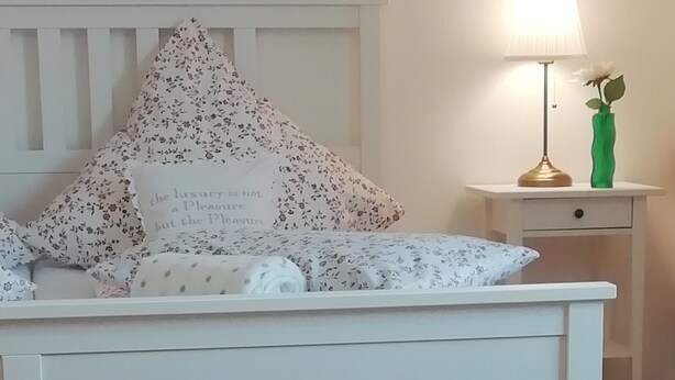 Een schaakbord in een kamer met een bed, kussens, een nachtkastje en een lamp.