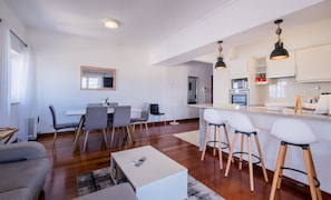 Une cuisine moderne dotée d’un îlot central, de tabourets de bar et d’un coin repas avec une table et des chaises.