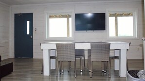 A room with a dining table, chairs, a TV, and a door. - Venice Blue Crab Lodge A (Waterfront) (Venice)