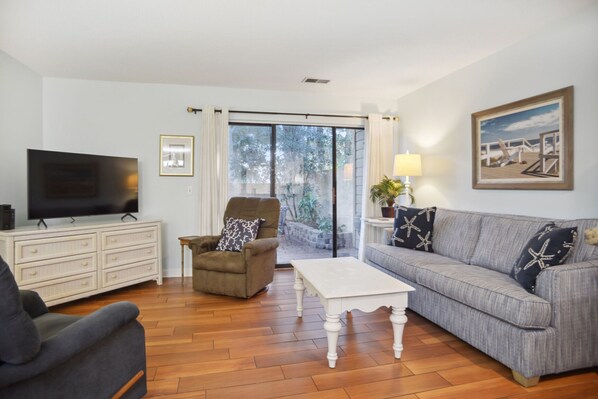 A living room with a television, a sofa, a chair, and a coffee table.