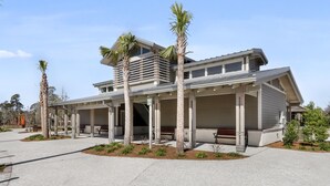 A modern two-story building with a covered patio area, palm trees, and a clear sky. - Hilton Head Beach Club - 3 Bedroom w/ a Private Patio! (Hilton Head Island)