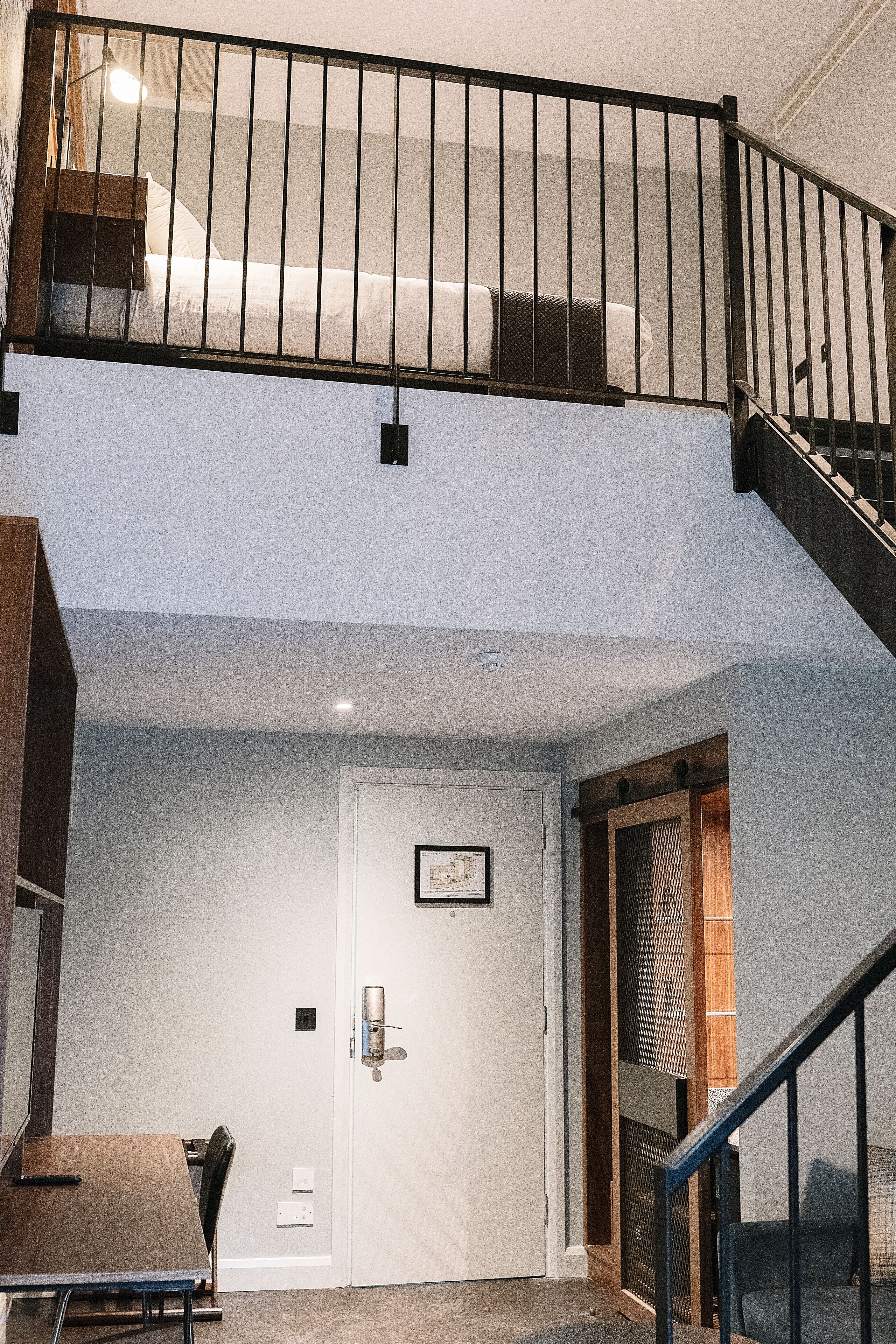 Un bâtiment à deux étages, doté d’un escalier, d’une porte ornée d’un cadre et d’une table entourée de chaises.