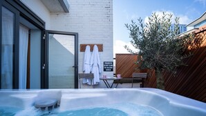A hot tub in a backyard with a white brick wall, a wooden fence, and a sign prohibiting climbing the balcony. - Telegraph Hotel - Coventry (Coventry)