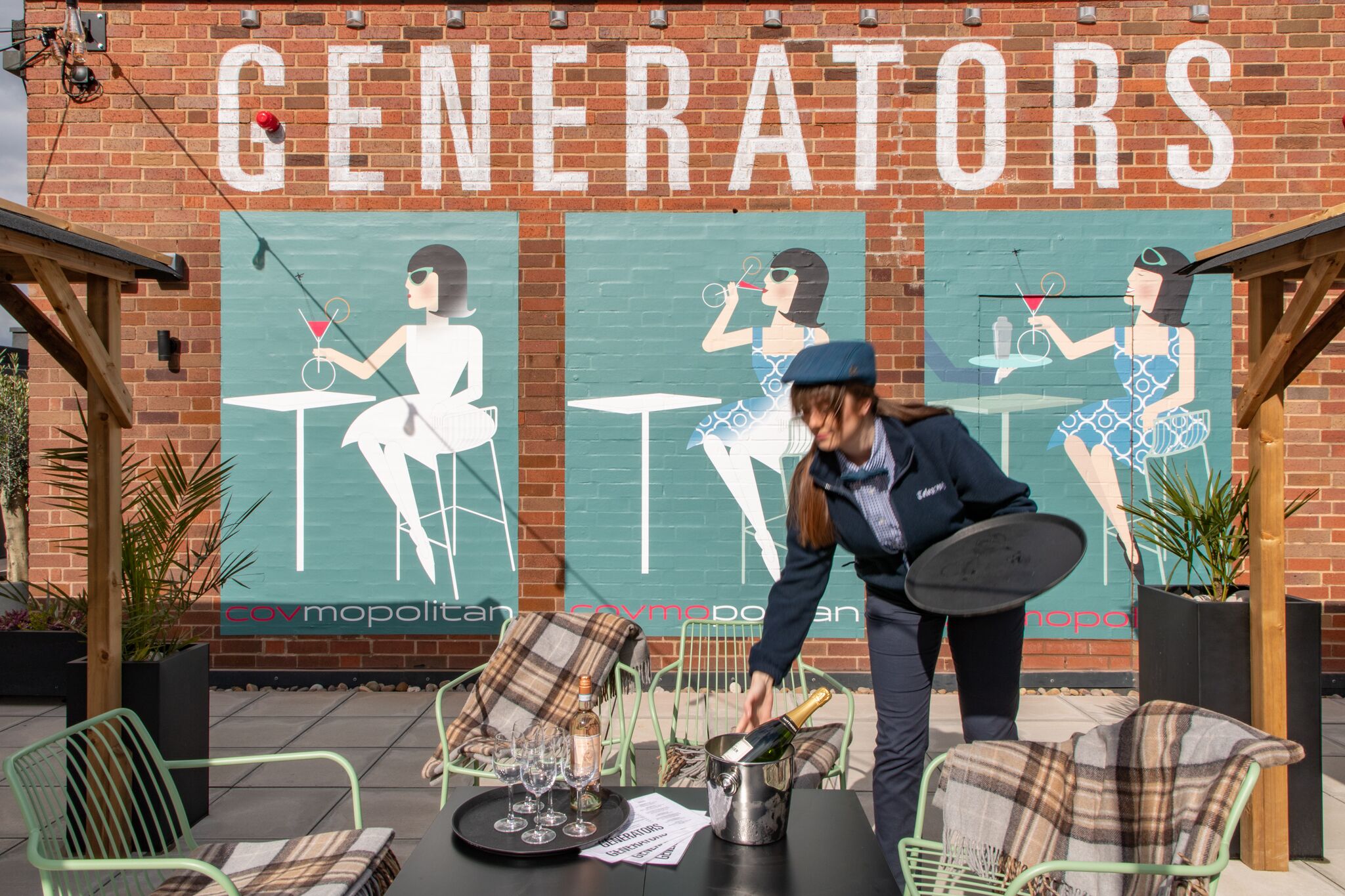 Een muurschildering met de tekst 'GENERATORS' en een bartender die drankjes inschenkt.