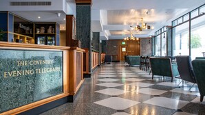 A hotel lobby with a checkered floor, a reception desk labeled "The Coventry Evening Telegraph," and a bar area with shelves. - Telegraph Hotel - Coventry (Coventry)