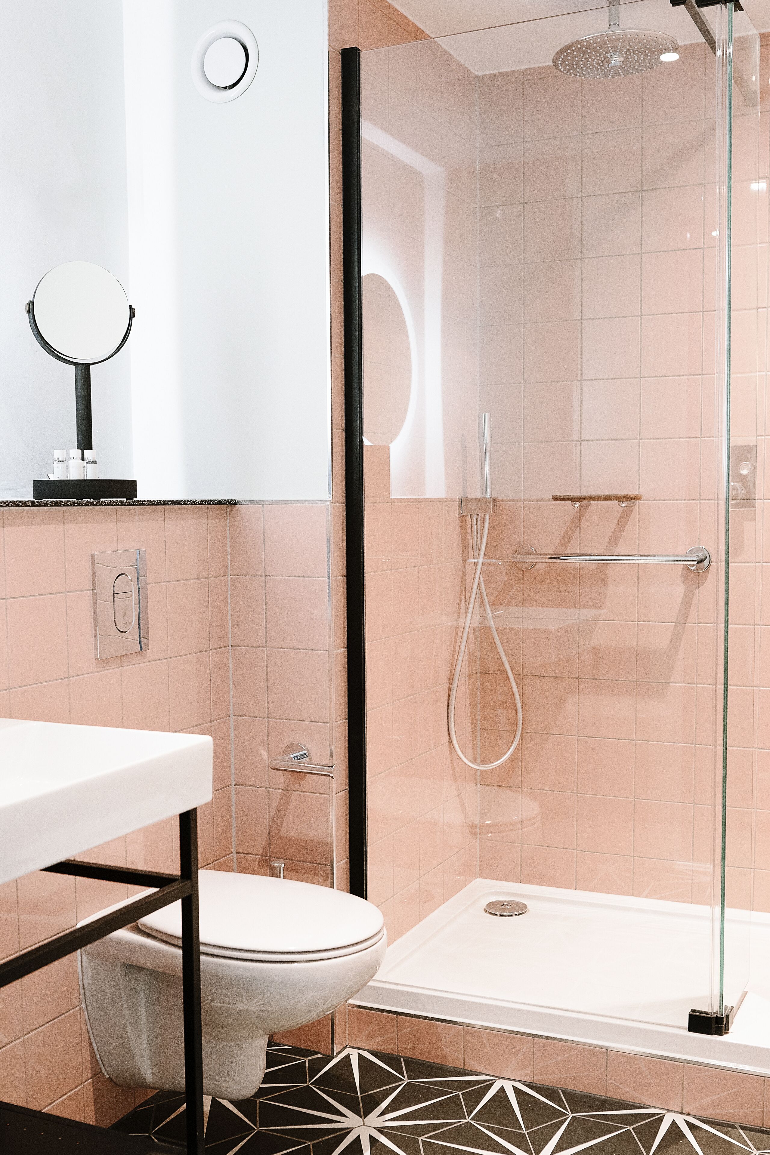 Un baño moderno con ducha de mampara de vidrio, inodoro y lavamanos.