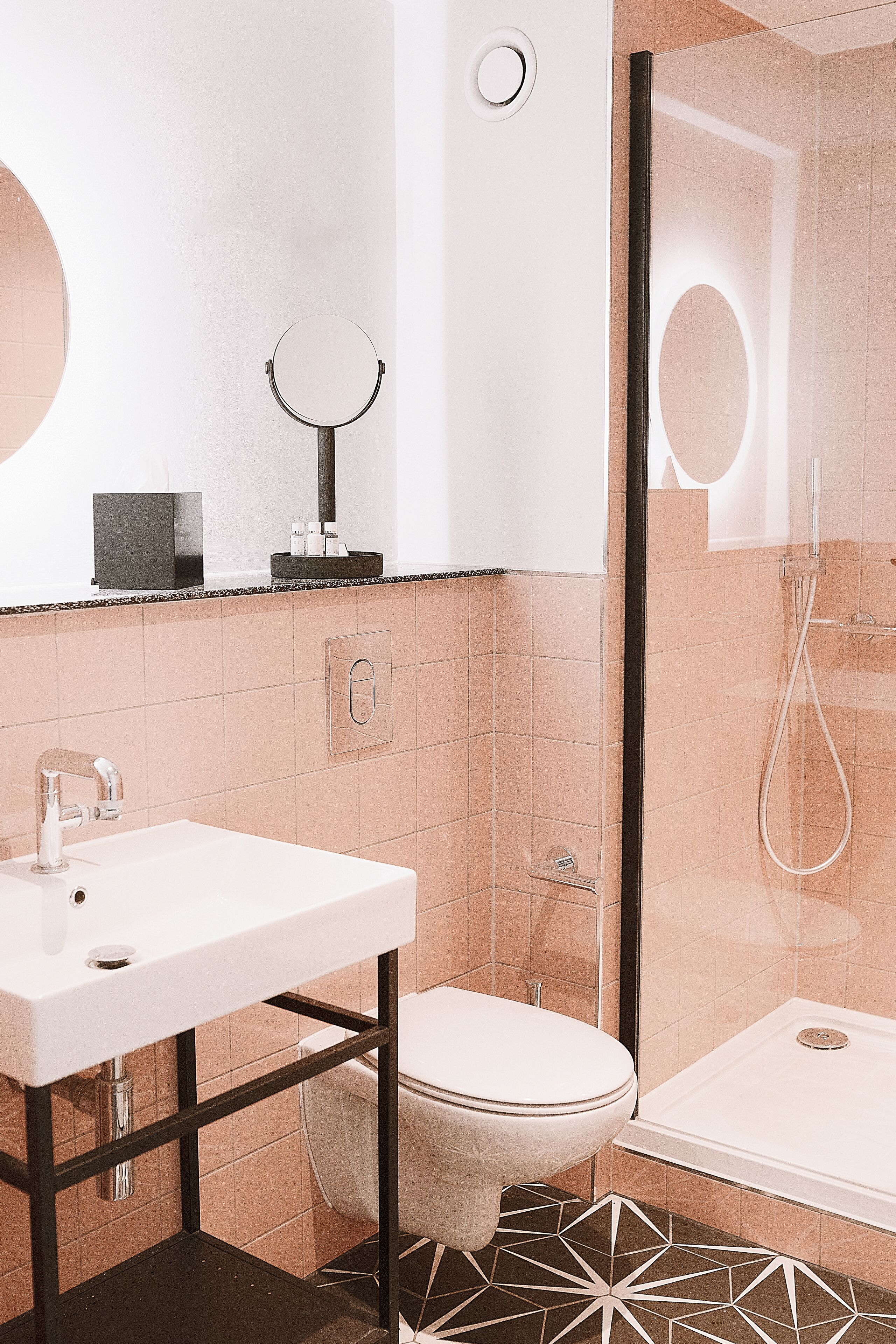 A modern bathroom with a white sink, toilet, and glass shower enclosure.