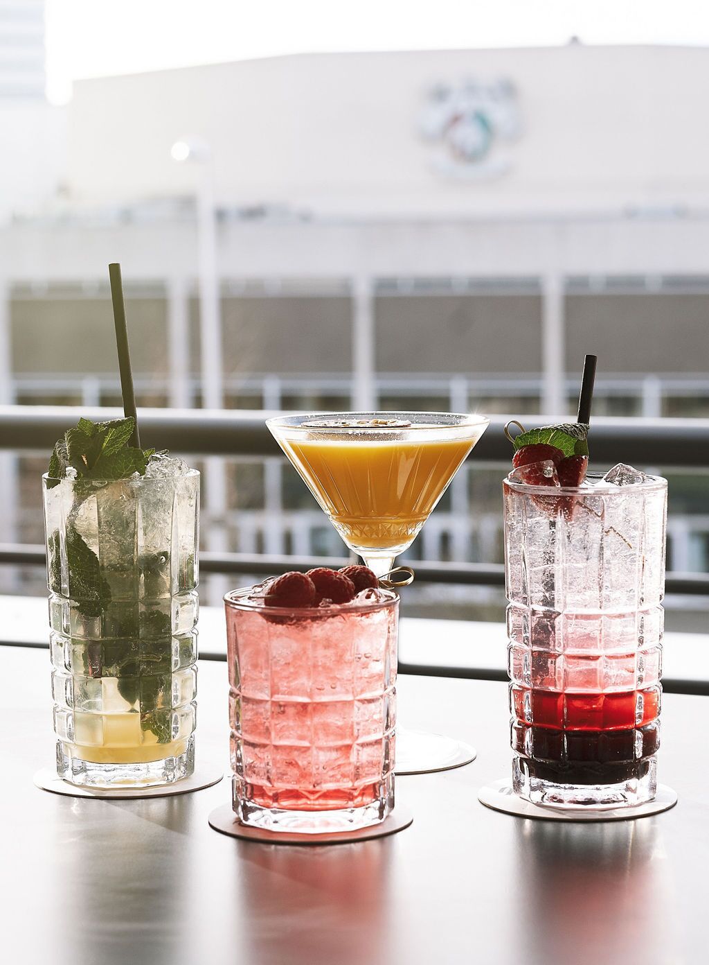 Three cocktails on a table with a city view in the background.