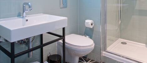 Un baño moderno con lavamanos blanco, inodoro y ducha con cerramiento de vidrio.