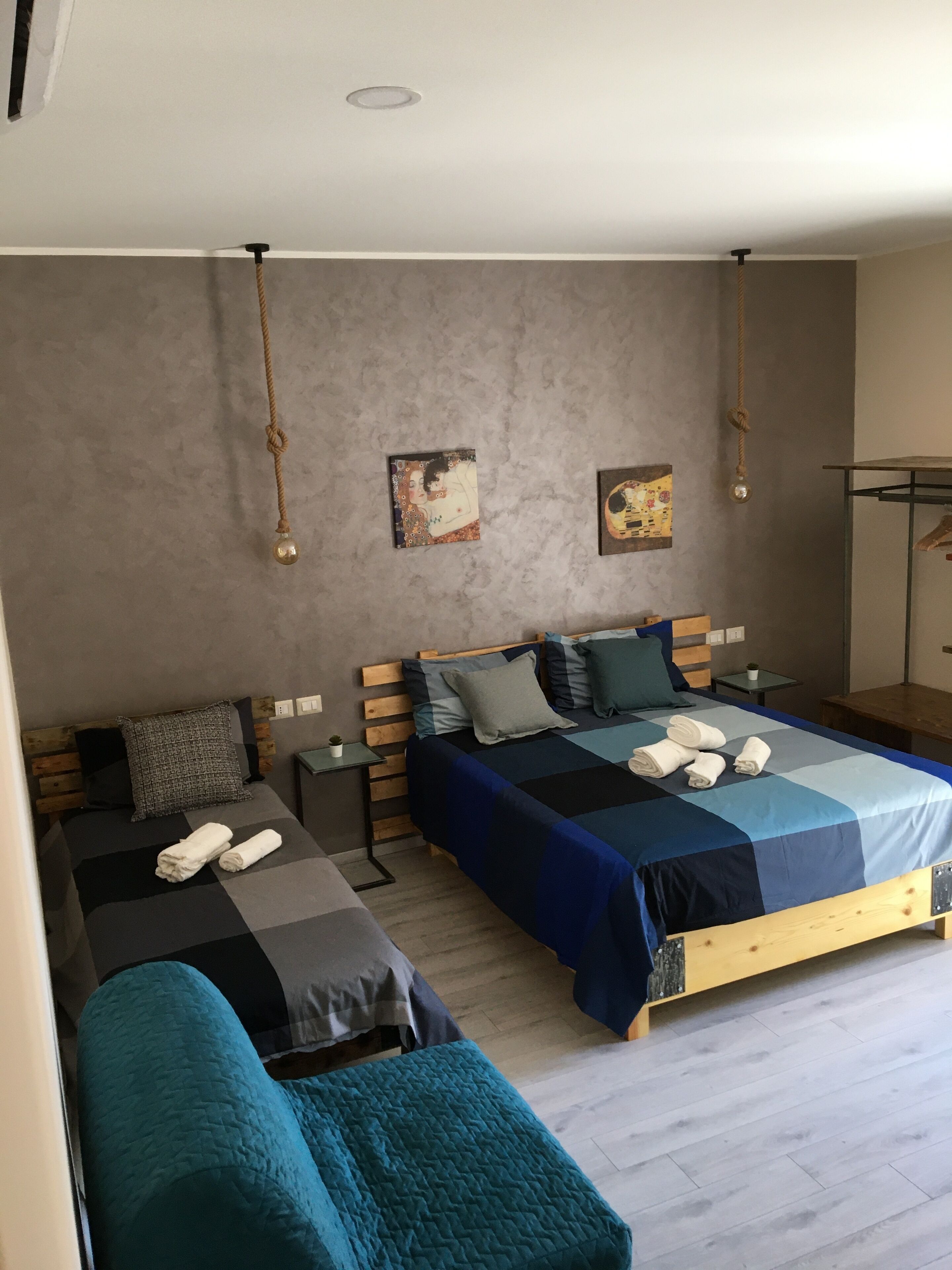 Un dormitorio moderno con dos camas, una mesita de noche pequeña y una lámpara colgante.