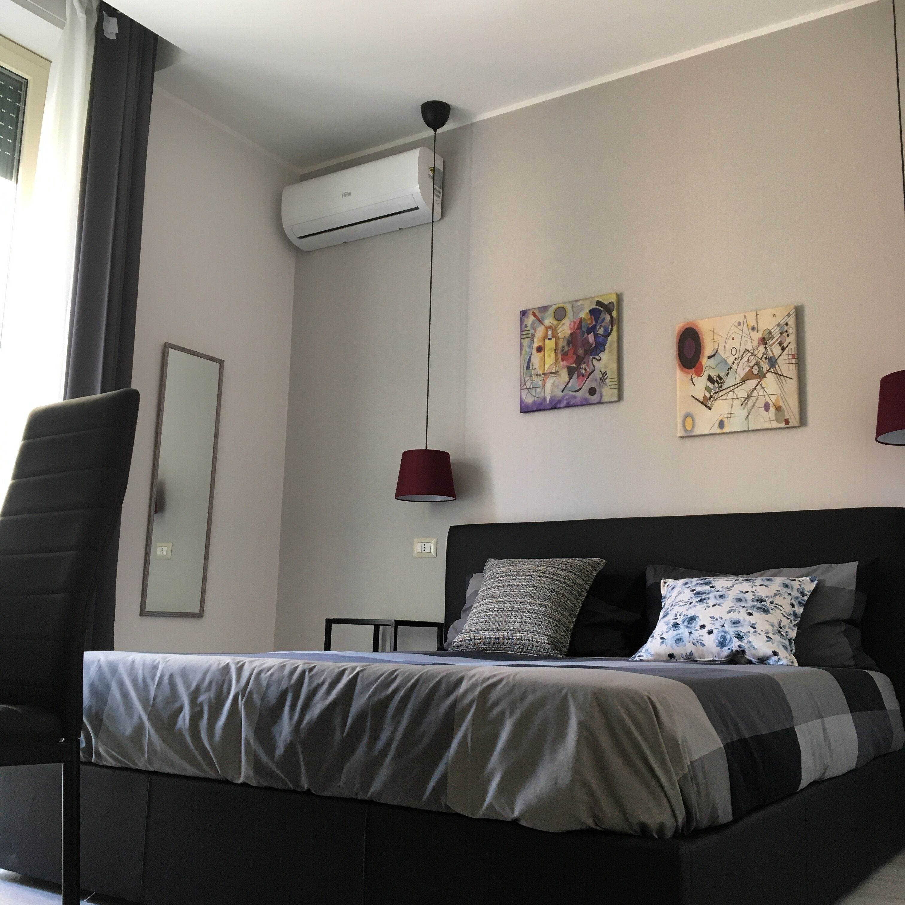 A modern bedroom with a bed, a desk, and an air conditioning unit.