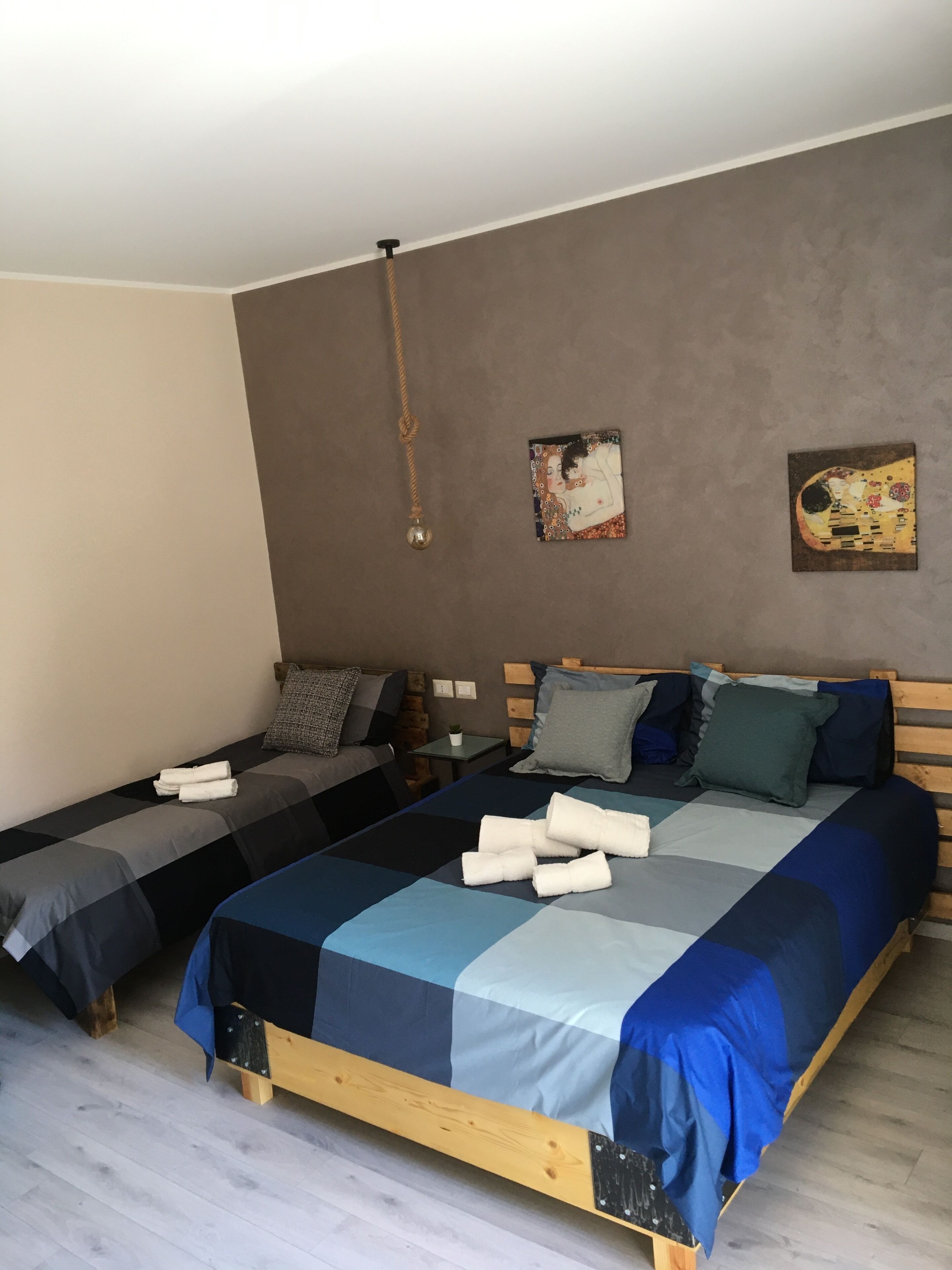 A bedroom with two beds, a wooden headboard, a small table, and a wall-mounted artwork.