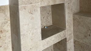 Ein Eckbereich eines Raumes mit beige gefärbten Marmorfliesen und einer weißen Wand.