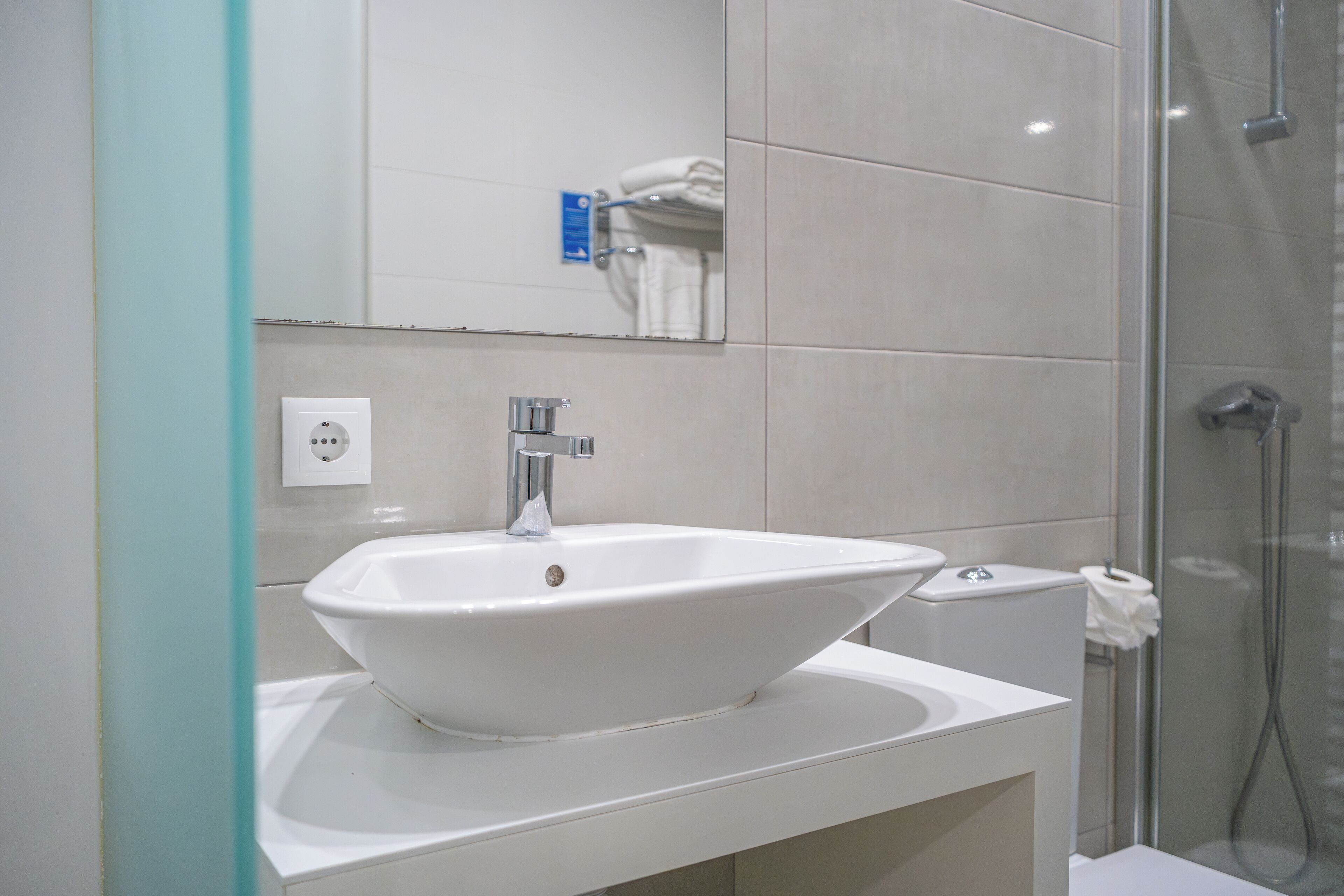 A bathroom with a white sink, a mirror, and a shower.