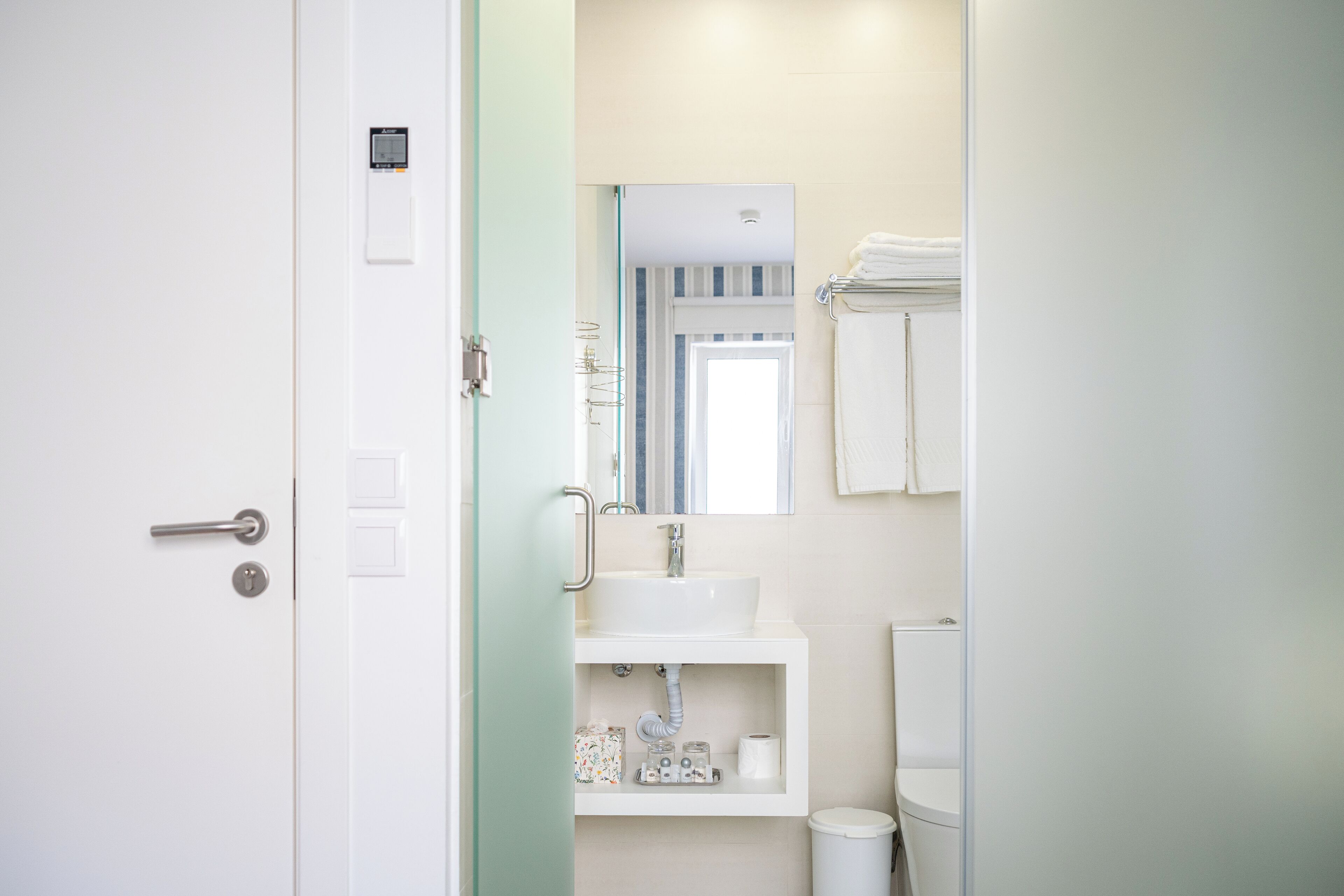 A bathroom with a white sink, mirror, and towel rack.