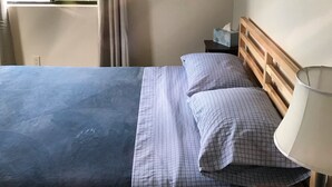 A hotel room with a bed, a nightstand, a lamp, a window with curtains, and a painting on the wall. - The Terrace House, country living. (Montgomery Creek)