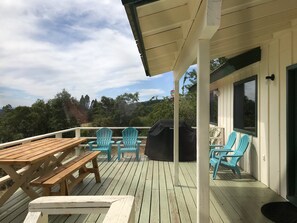 A wooden deck with picnic tables and chairs, a barbecue grill, and a view of the surrounding landscape. - The Terrace House, country living. (Montgomery Creek)