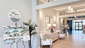 A spacious lobby with a reception desk, white armchairs, and a large painting on easels. - BT 3322 Fountain/Pond View Condo-Paradise Vacation Rental in Ocean Village (Fort Pierce)