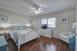 Ein Schlafzimmer mit Bett, Kommode, Fernseher und einem Sessel.