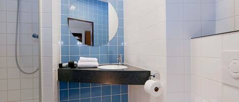 A bathroom with a shower, a sink, and a mirror.