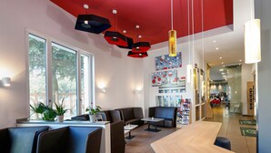 Un restaurante moderno con cabinas de cuero negro, una barra de madera y detalles rojos en el techo.