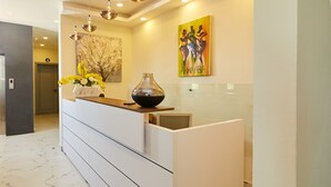 A reception desk with a vase of flowers, a painting, and a modern interior design.