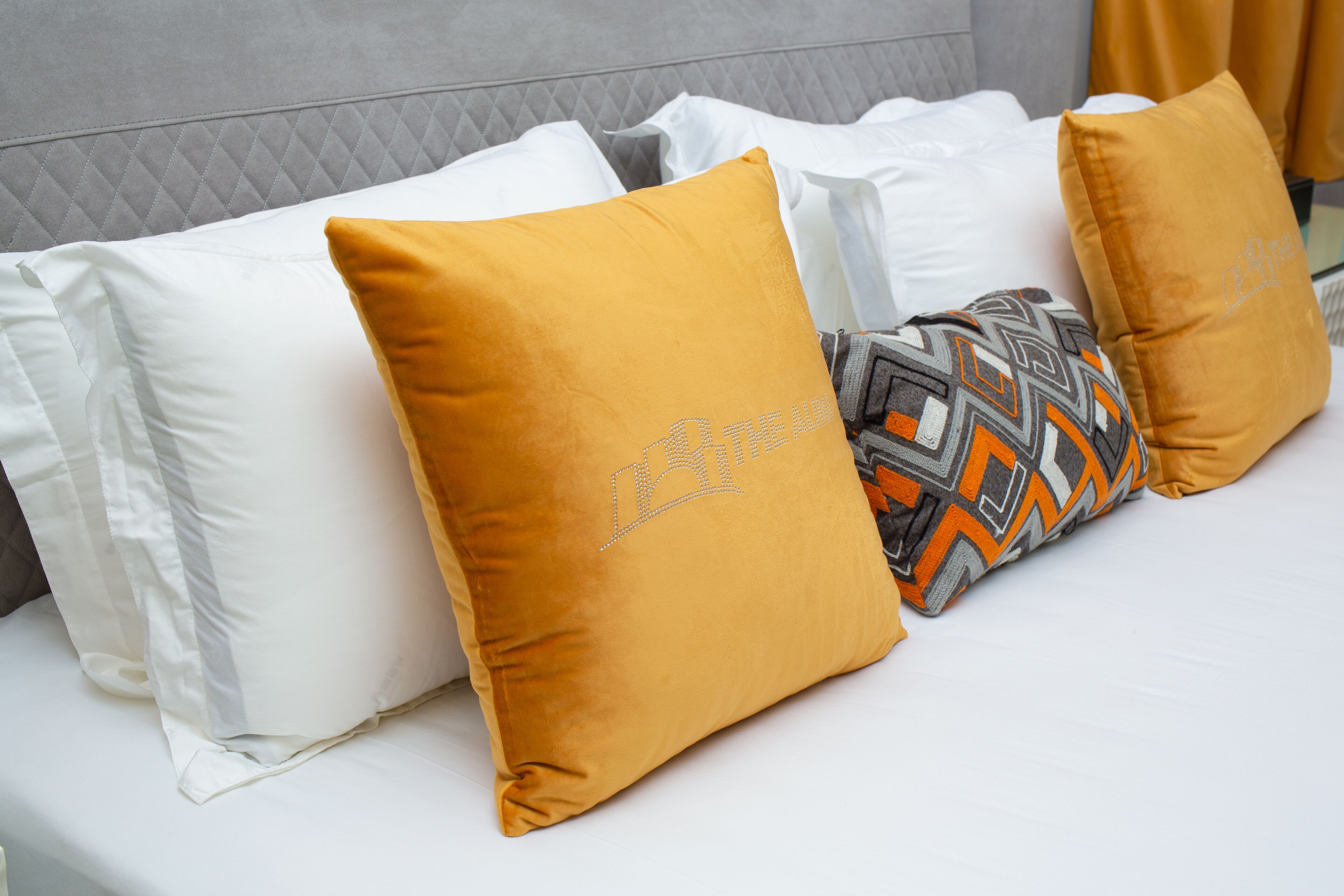A bed with white and mustard-colored pillows, one with a geometric pattern.
