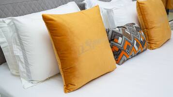 A bed with white and mustard-colored pillows, one with a geometric pattern.