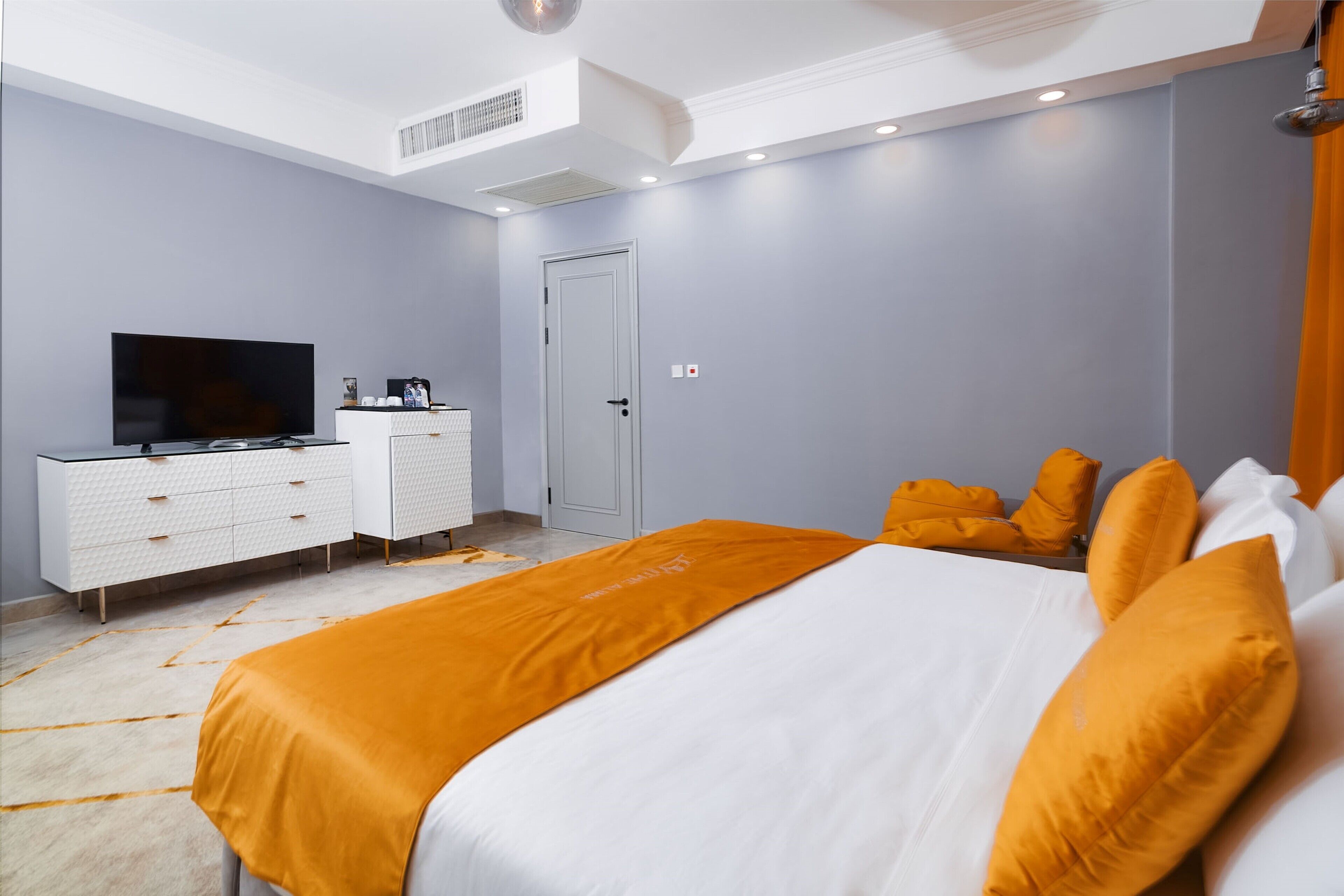 Une chambre à coucher avec un lit, une télévision, une commode et une porte.