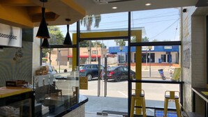 A restaurant interior with a counter, yellow stools, and a view of the street outside.