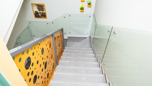 A modern staircase with glass railings and a yellow perforated wall.