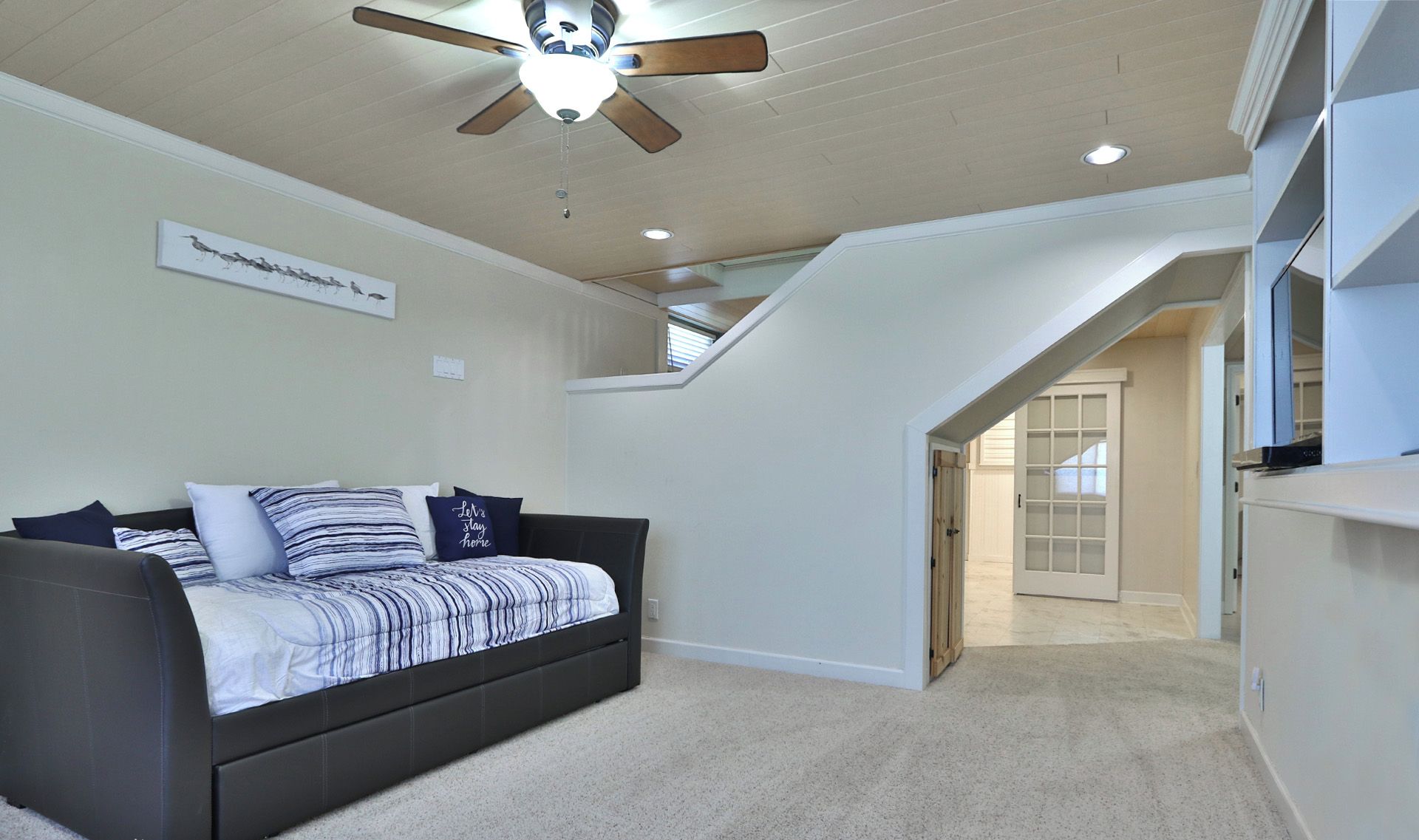 Un dormitorio con cama, ventilador de techo y una escalera que conduce a un nivel superior.