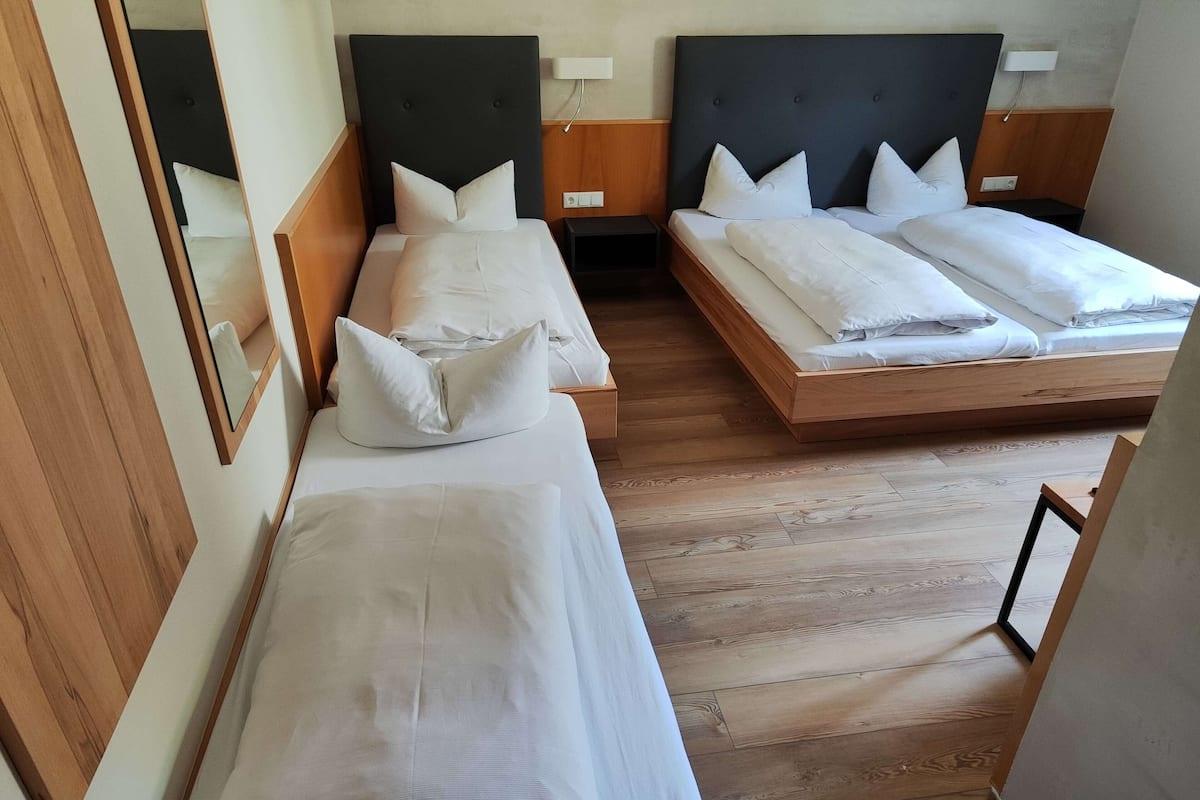 Une chambre d’hôtel avec deux lits simples, un plancher en bois et un miroir sur un des murs.