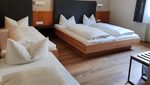 Ein Hotelzimmer mit zwei Betten, Holzboden und einem fenster mit Vorhängen.