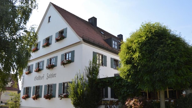 Ein weißes Gebäude mit grünen Fensterläden und Blumenkästen an den Fenstern.