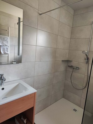 Un baño moderno con un lavamanos blanco, un espejo y una zona de ducha.