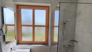 Ein modernes Badezimmer mit Dusche, Waschbecken und Fenster.