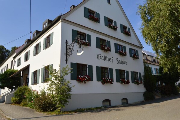 Un edificio blanco con contraventanas verdes y macetas con flores, que dice 'Gaffhof Sablier'.