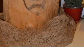 Eine Holzskulptur mit Gesicht auf einem Jutbeutel.