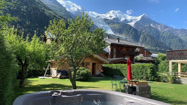 A hot tub in a garden with a mountain backdrop.