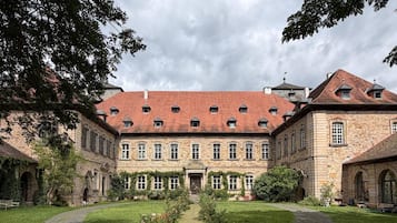 A courtyard with a central pathway leading to a building with a red-tiled roof and stone walls.