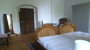 A bedroom with a wooden bed, a chair, a mirror, and a door. - Ferienzimmer im Schloss Burgpreppach (Burgpreppach)
