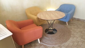 Una habitació amb una taula rodona de fusta, una butaca groga, una butaca blava i una butaca taronja.